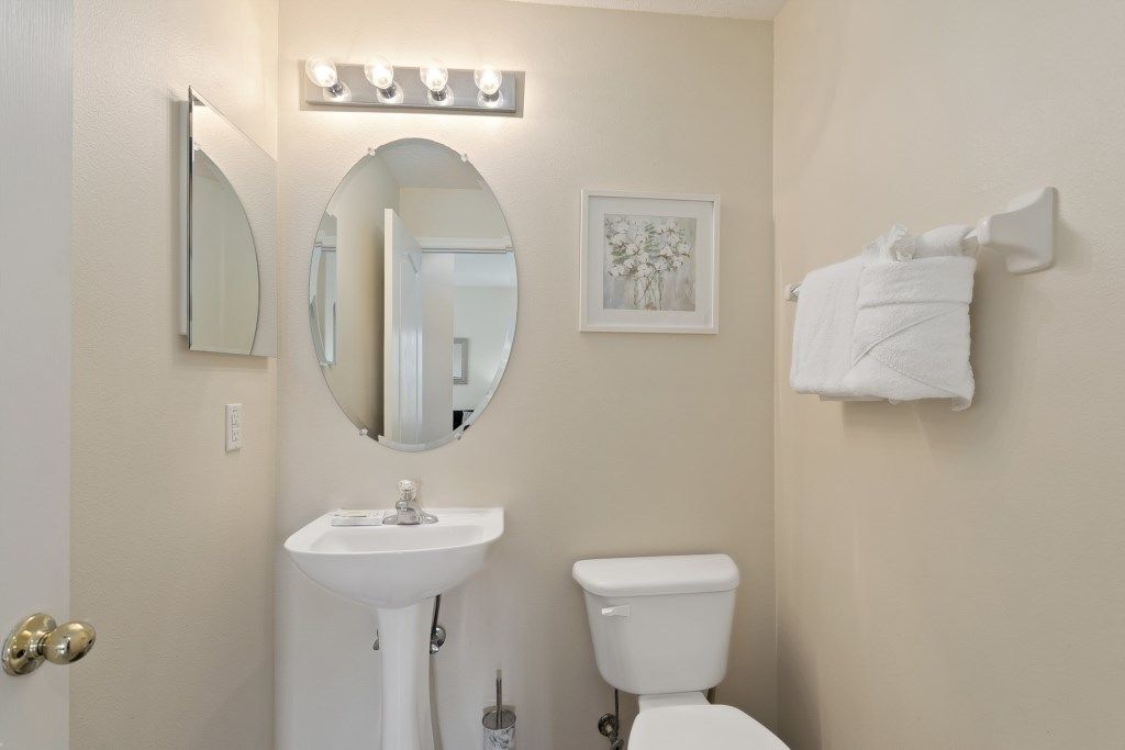 A bathroom with a white sink, a toilet, a large mirror, and a towel rack.