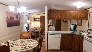 Una cocina compacta con armarios de madera, lavavajillas y una zona de comedor con mesa y sillas.