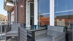 An outdoor patio with wicker furniture and a glass table. - Vacation apartment Barbara (Wittmund)