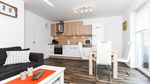 A modern apartment with a living room, kitchen, and dining area. - Vacation apartment Barbara (Wittmund)