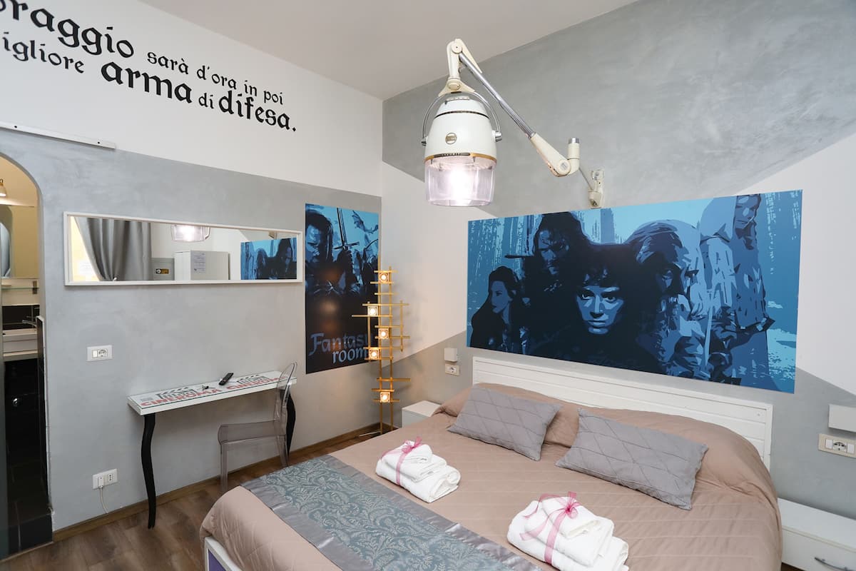 A bedroom with a bed, a desk, a mirror, and a wall with a poster.