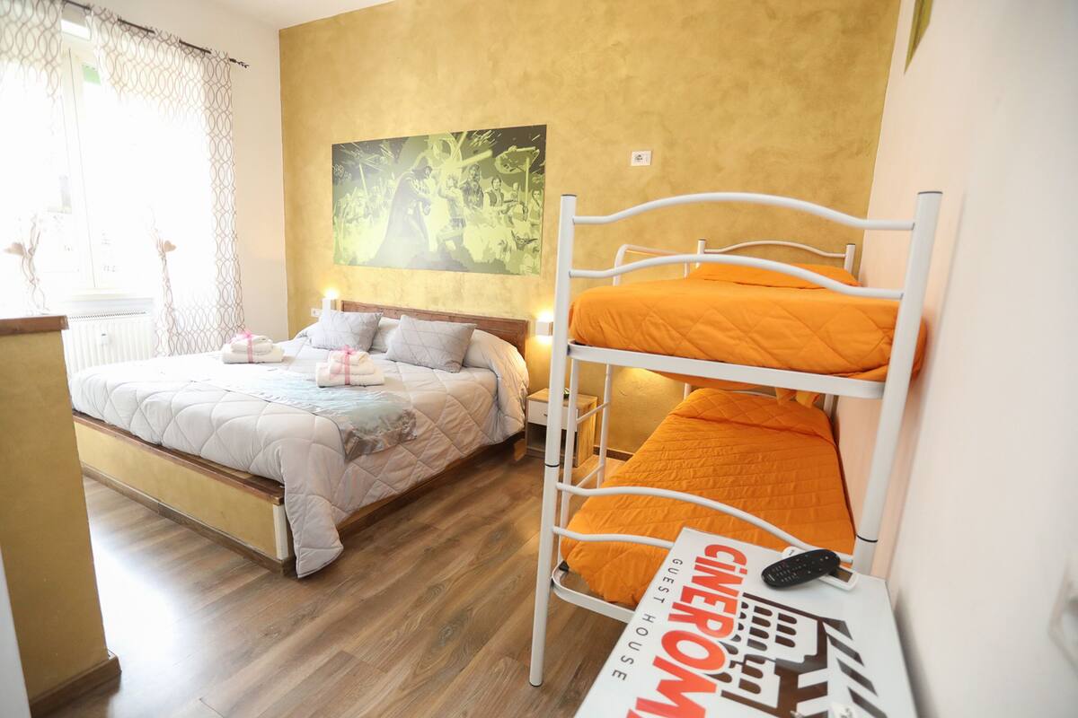 A guest room with a bunk bed, a single bed, and a painting on the wall.