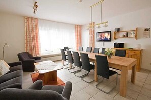 Un salon moderne comprenant un coin repas, un téléviseur et une bibliothèque.