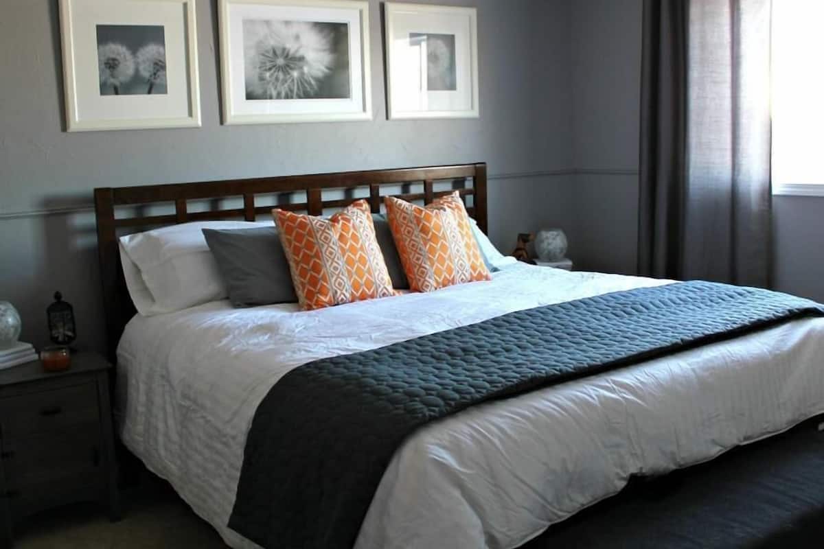 A bedroom with a large bed, a wooden headboard, and three framed pictures on the wall.