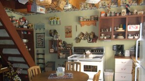 Une cuisine avec une table à manger en bois, des chaises, une cuisinière et divers ustensiles de cuisine rangés sur des étagères.