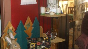 Une pièce chaleureuse avec un mur rouge, une chaise en bois, une petite table ornée d’un objet décoratif et une étagère contenant divers objets.
