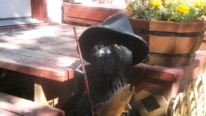 Une statue de jardin représentant un ours tenant un poisson, un banc en bois et un jardinière avec des fleurs.