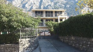 A two-story building with a balcony, surrounded by stone walls and greenery. - Apartments Vojvoda (Kotor)