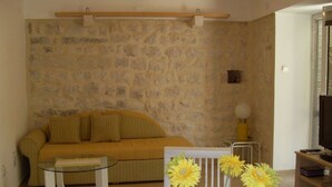 A living room with a stone wall, a sofa, a glass coffee table, and a lamp. - Apartments Vojvoda (Kotor)