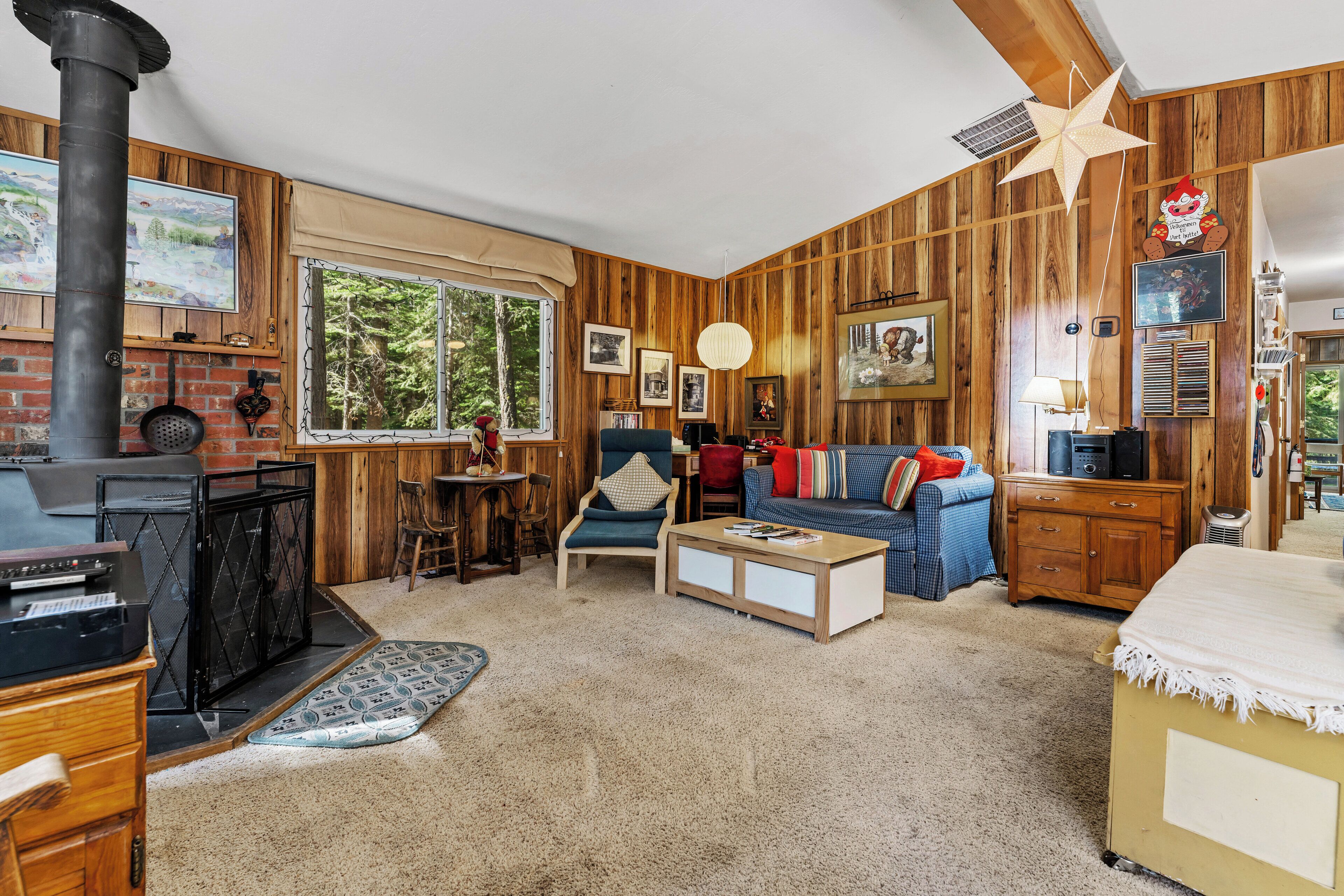 A cozy living room with a fireplace, wooden walls, a sofa, and a coffee table.