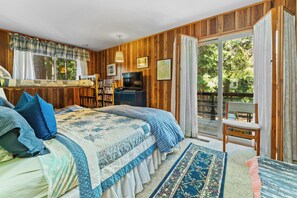 Une chambre à coucher avec un lit, une télévision, un bureau et une vue sur l’extérieur.