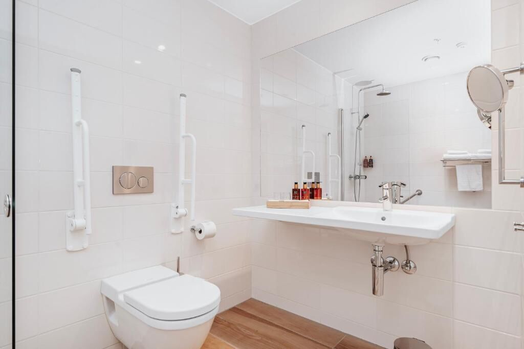 A modern bathroom with a white toilet, a sink with a mirror, and a shower area.