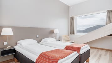 Une chambre d’hôtel moderne avec deux lits, un bureau et une fenêtre donnant sur une vue sur la montagne.