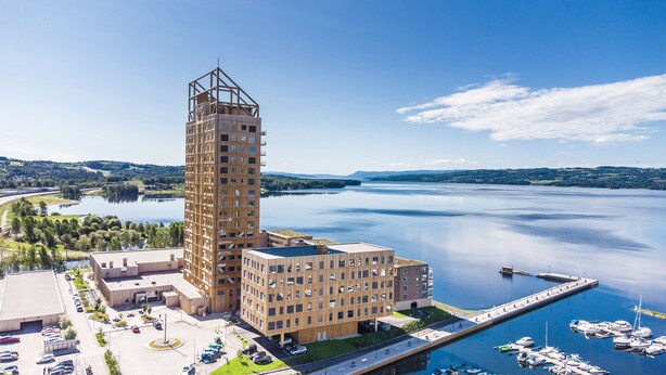 Et moderne, højt hotel med et markant tårn, beliggende ved en rolig sø med lystbådehavn.