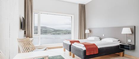 Una habitación de hotel moderna con un ventanal grande, una cama, un escritorio y una silla.