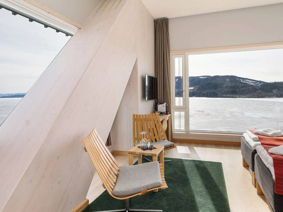 Ein Zimmer mit großem Fenster, einem Bett, einem Schreibtisch und einem Stuhl.