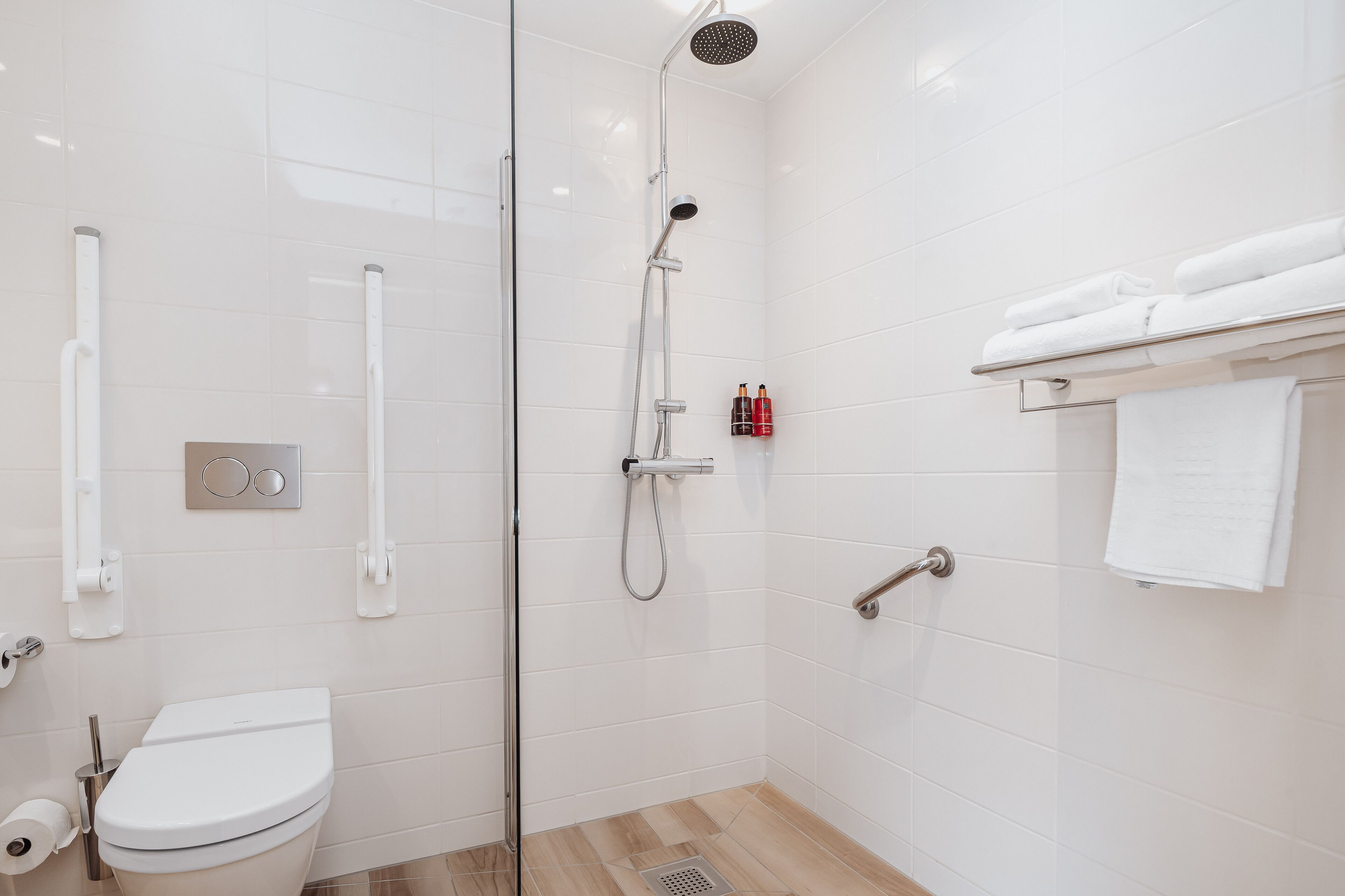 A modern bathroom with a glass-enclosed shower, a toilet, and a towel rack.