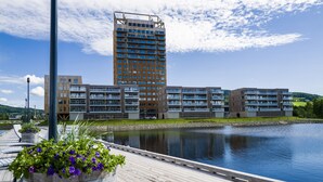 Et moderne hotel med flere etager, havudsigt og en træterrasse med blomsterkasser.