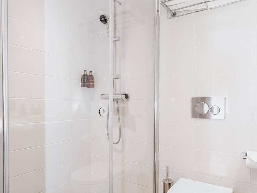 A modern bathroom with a glass-enclosed shower, a white toilet, and a towel rack.