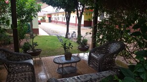Eine Terrasse mit Korbmöbeln, Topfpflanzen und Blick auf ein Gebäude im Hintergrund.