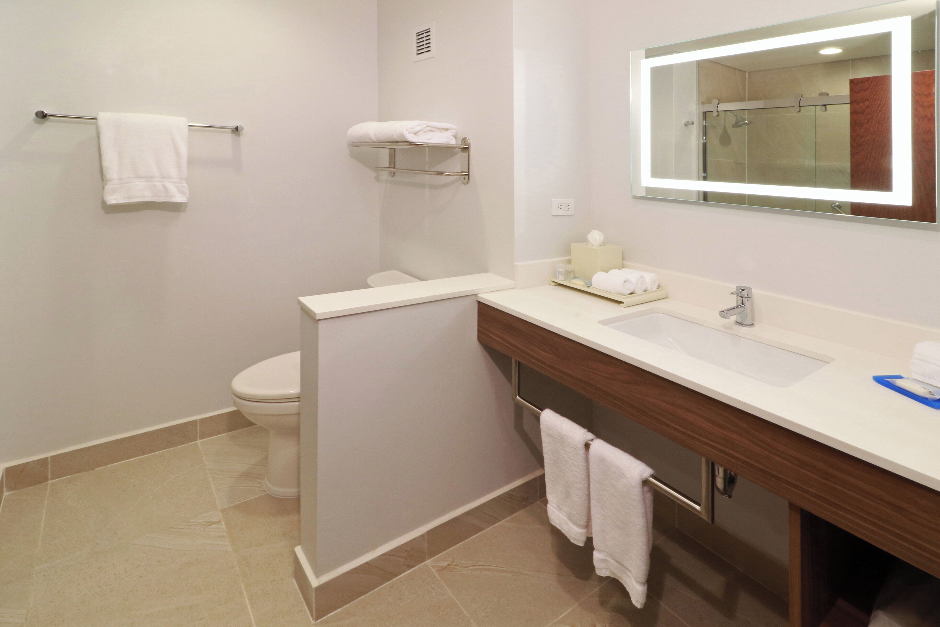 Une salle de bain moderne équipée d’un WC, d’un lavabo, d’un miroir et d’un porte-serviettes.