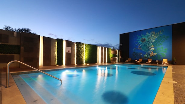 A swimming pool with a metal ladder, surrounded by walls with vertical light strips and a mural. - Holiday Inn Express & Suites Ensenada Centro by IHG (Ensenada)