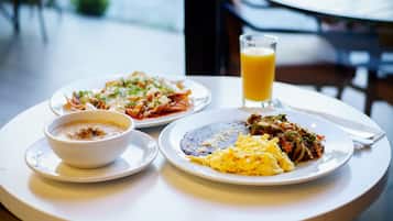 Una mesa con dos platos de comida, un tazón de sopa y un vaso de jugo de naranja.