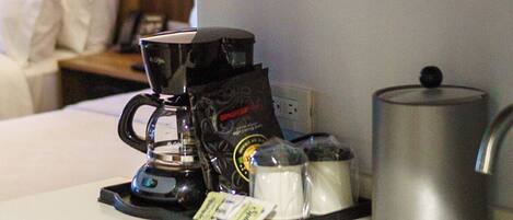 Une petite cuisine équipée d’une machine à café, d’une bouilloire et d’un four à micro-ondes, le tout installé au-dessus de l’évier.