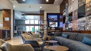 A modern lounge area with sofas, chairs, and a bar area with a television. - Holiday Inn Express & Suites Ensenada Centro by IHG (Ensenada)