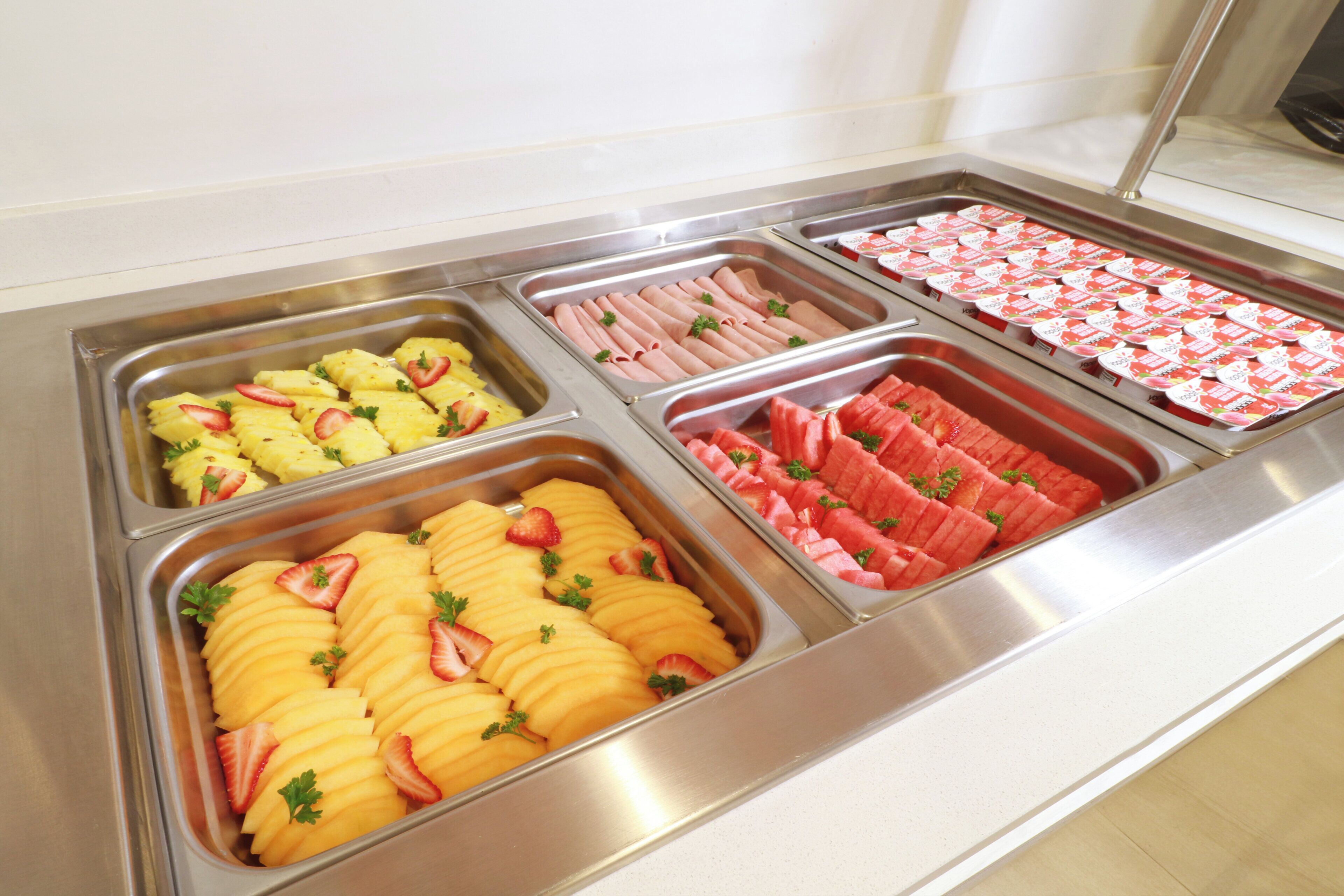 Un buffet proposant une variété de plats, notamment des fruits et des viandes.