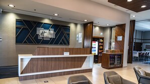 A reception area with a modern desk, seating, and a bar area with a refrigerator. - Holiday Inn Express & Suites Ensenada Centro by IHG (Ensenada)