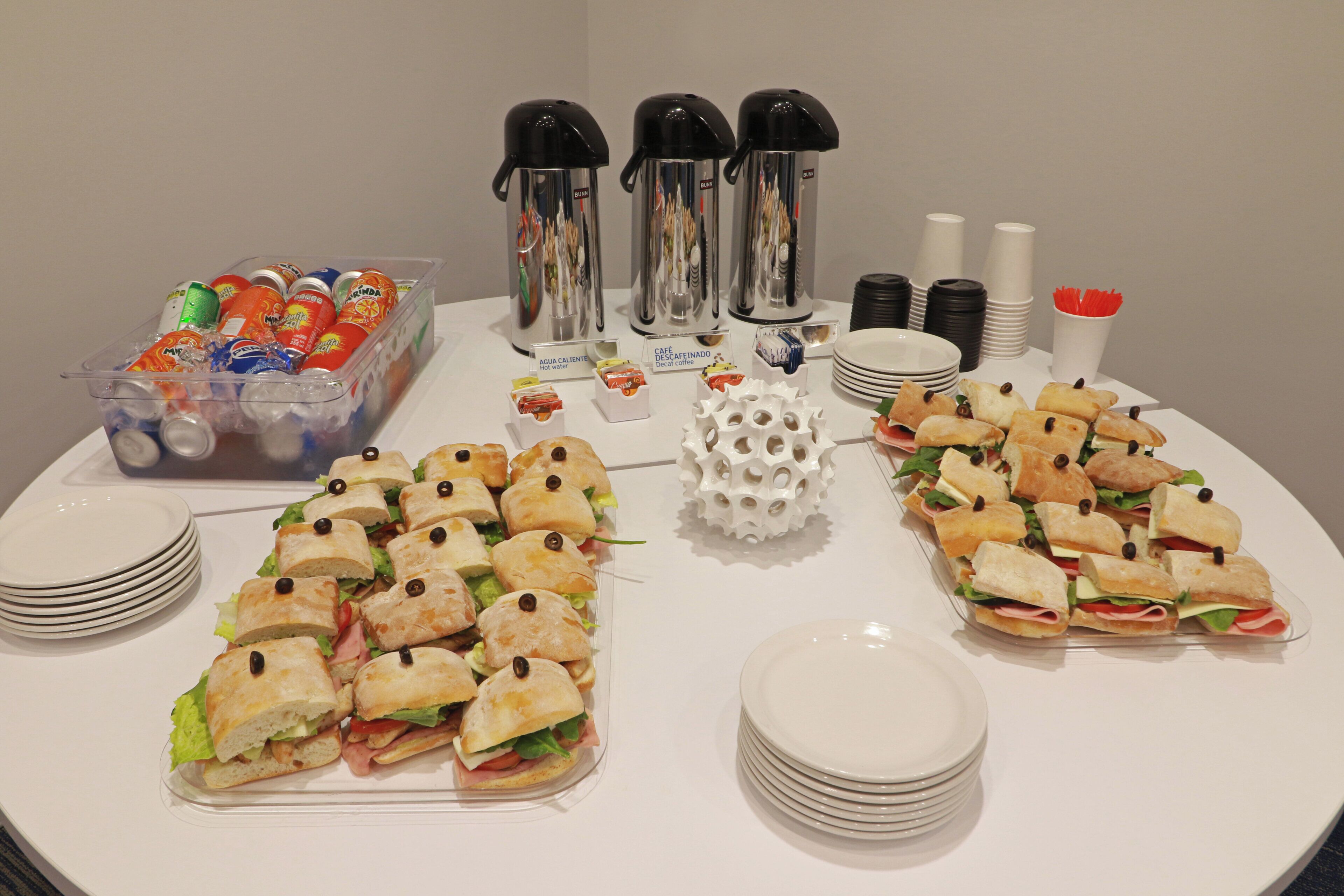 A buffet table with sandwiches, hot water, decaffeinated coffee, and various beverages.