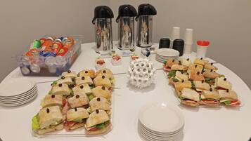 A buffet table with sandwiches, hot water, decaffeinated coffee, and various beverages.