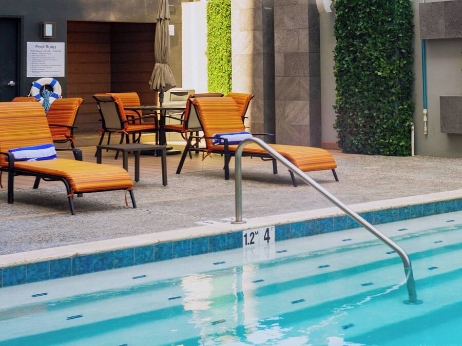 Uma área de piscina com espreguiçadeiras e escada para piscina.
