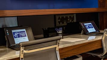 A desk with two laptops displaying the Holiday Inn Express & Suites logo, a keyboard, a mouse, and a pen holder with pens.