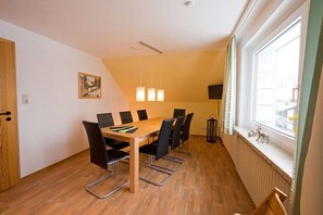 Un salón de conferencias con una mesa de madera, sillas negras, un cuadro en la pared y una ventana con vistas.