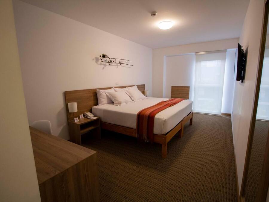 Ein Hotelzimmer mit Bett, Nachttisch, Lampe und einem Wandbild.