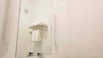 A modern bathroom with a white sink, a large mirror, and a granite countertop.