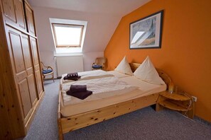 A bedroom with a wooden bed, a window, a radiator, and a chair.