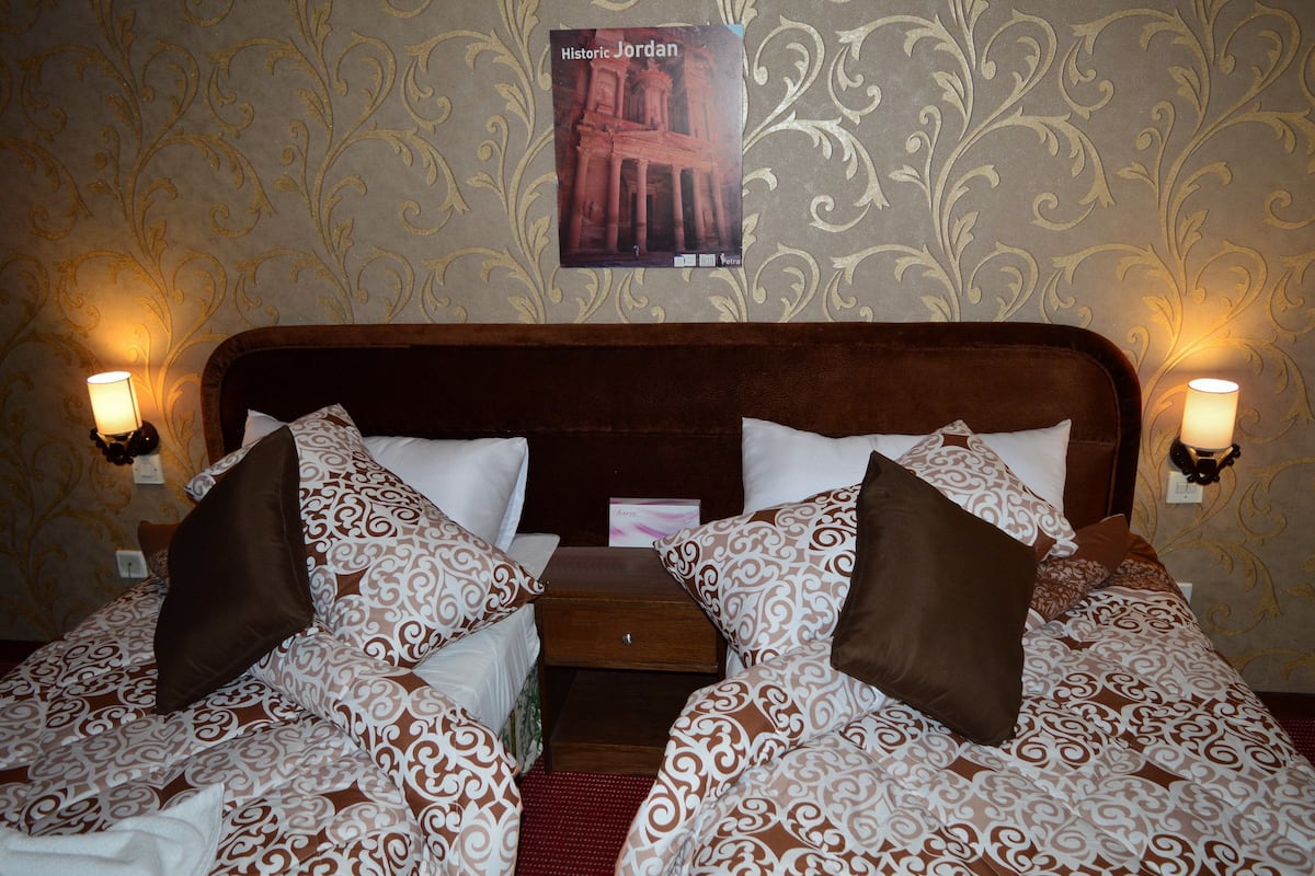 A double bed with patterned bedding, two bedside tables, and wall-mounted lamps.
