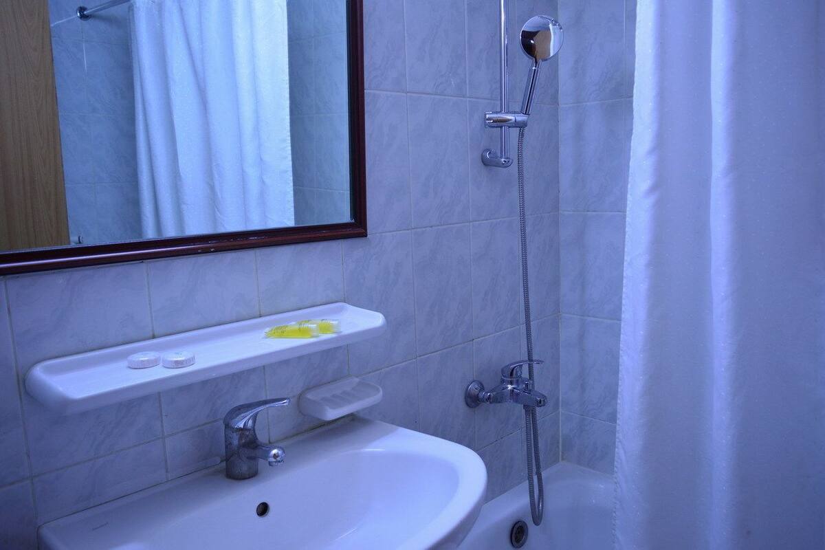 A bathroom with a sink, mirror, shower, and a towel rack.