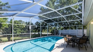 Piscina exterior techada con área de patio y una mesa con sillas.