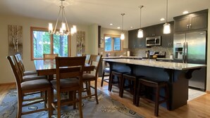 A modern kitchen with a central island, dark cabinetry, stainless steel appliances, and pendant lighting.