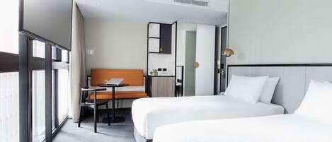 Une chambre d’hôtel avec deux lits, une petite table, une chaise, un bureau et un miroir.