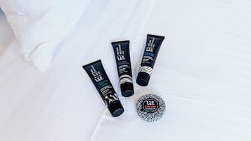 Four skincare products and a body bar on a white bed.