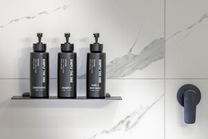 Three black bottles of VETIVER products on a shelf against a marble wall.