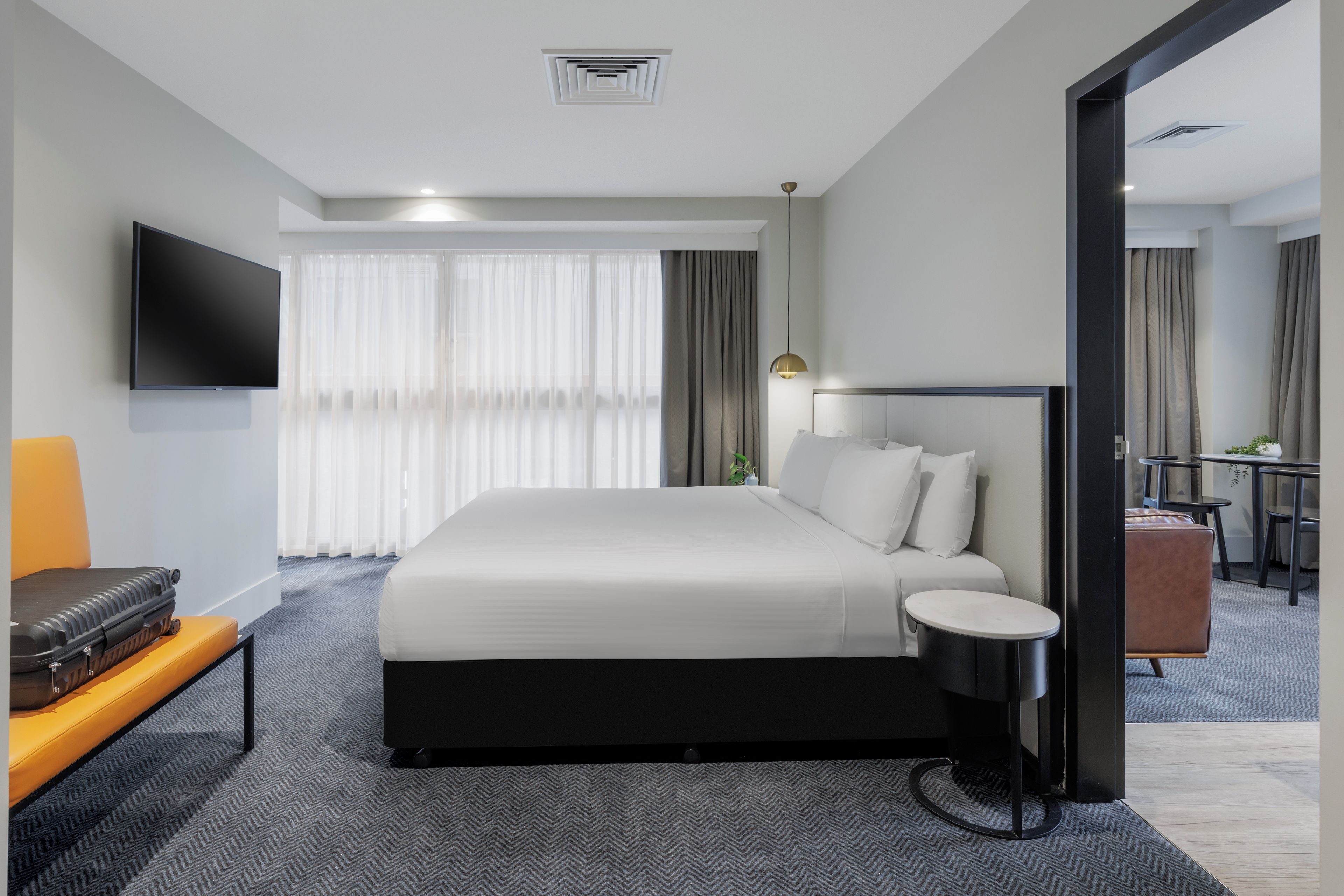 A hotel room with a large bed, a flat-screen TV, a desk with a chair, and a small table.