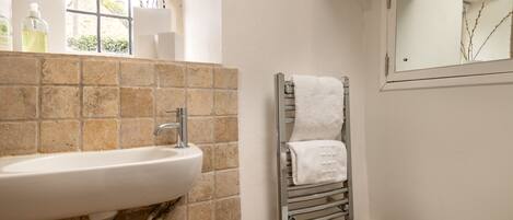 A bathroom with a white sink, a towel rack, and a window with branches.