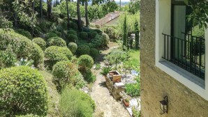 Un exuberante jardín con un muro de piedra, una jardinera de ladrillo y vista a un edificio lejano.