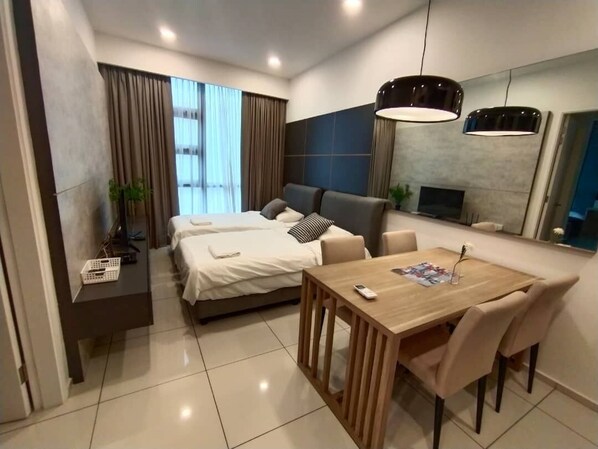 Une chambre d’hôtel moderne équipée d’un lit, d’une table à manger avec des chaises, d’une télévision et d’un grand miroir.